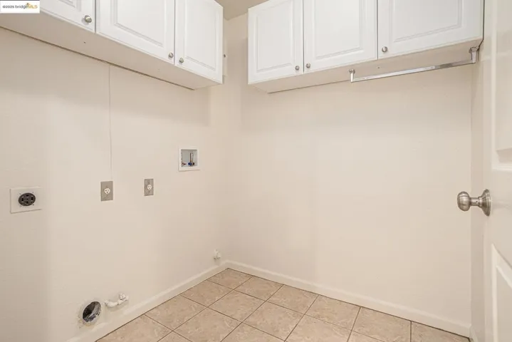 Washroom featuring gas or electric hookups, washer hookup, light tile patterned floors, and upper cabinet space