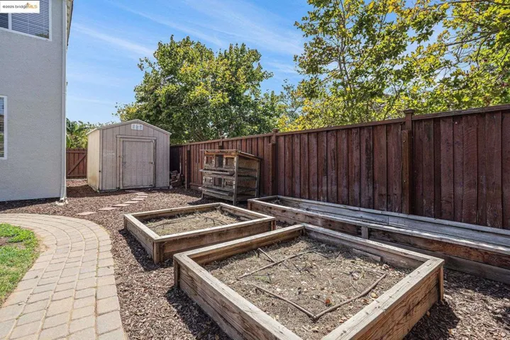 Fenced backyard with a storage unit and a garden