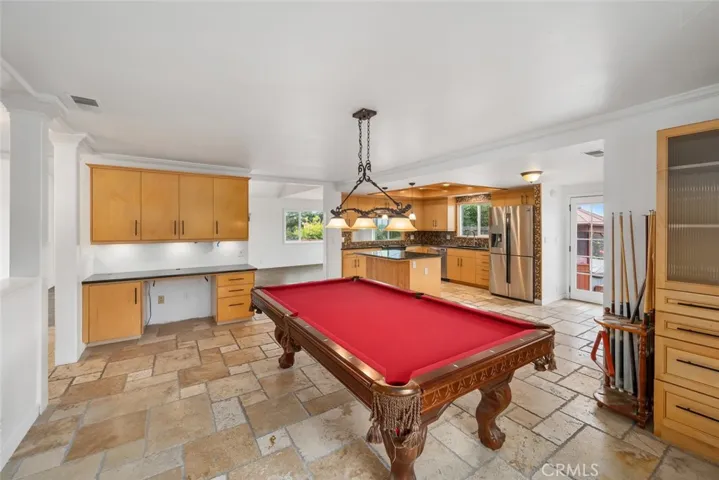 Travertine flooring in the open concept kitchen with built in cabinets and entry desk