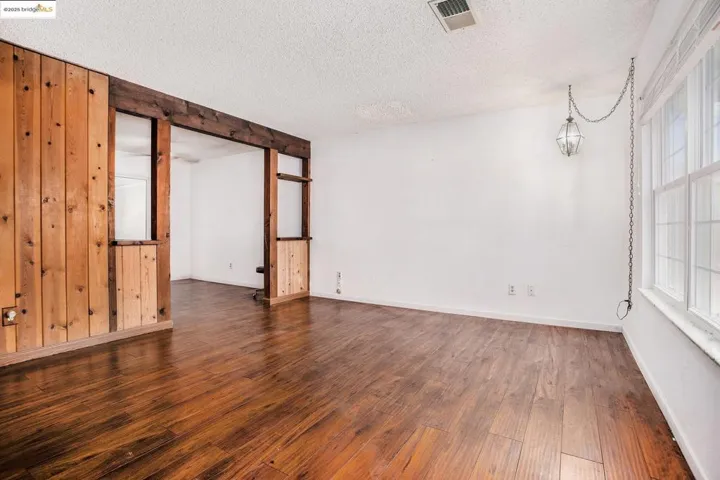 Spare room with dark wood-style floors, a textured ceiling, and wood walls