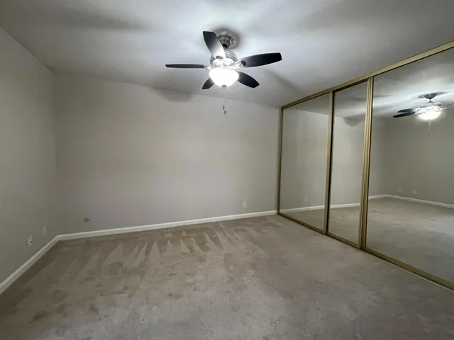 Bedroom with a closet, light carpet, and ceiling fan
