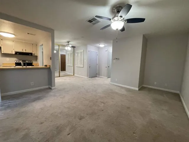 Unfurnished living room with carpet flooring and a ceiling fan