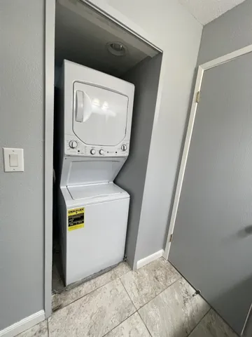 Washroom featuring estacked washer and dryer and baseboards