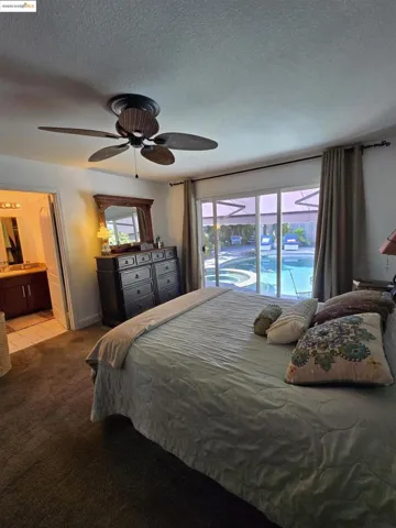 Bedroom featuring a textured ceiling, carpet flooring, a ceiling fan, and connected bathroom
