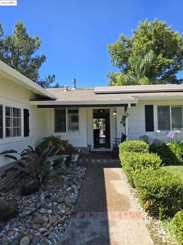 Property entrance featuring roof with shingles and solar panels