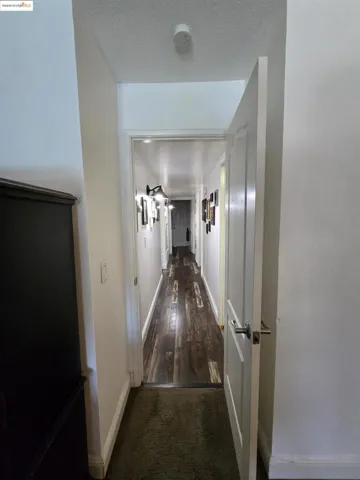 Hallway with dark carpet and a textured ceiling