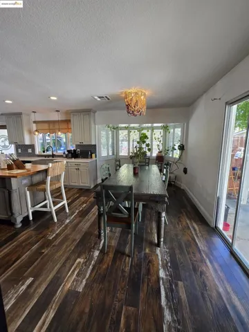 Dining area featuring dark wood-type flooring, a chandelier, and a textured ceiling