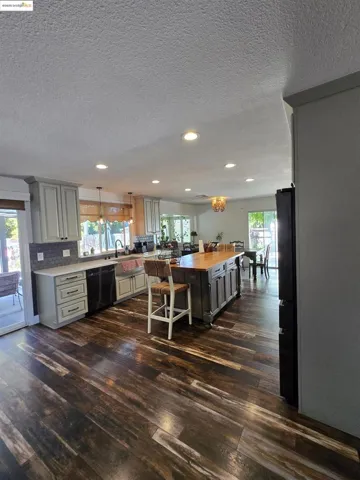 Kitchen featuring butcher block counters, dark wood-style floors, gray cabinetry, black appliances, and a textured ceiling