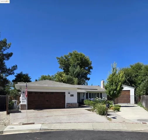 Single story home with driveway, an attached garage, brick siding, and solar panels