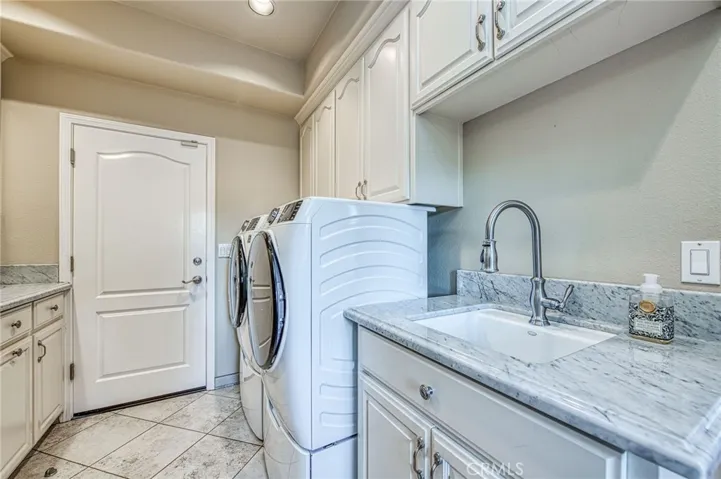 Laundry room with storage, ample counter space, and marble counter utility sink