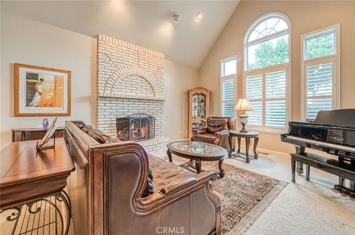 Formal living room with grand fireplace and large windows with view of front landscaping