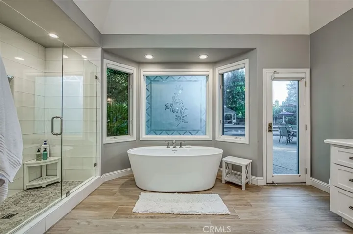 Primary en-suite bathroom displaying view to back yard landscaping, and entry door directly to pool