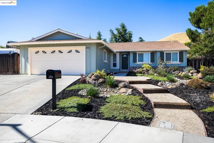 Ranch-style home with an attached garage, concrete driveway, a mountain view, a shingled roof, and board and batten siding