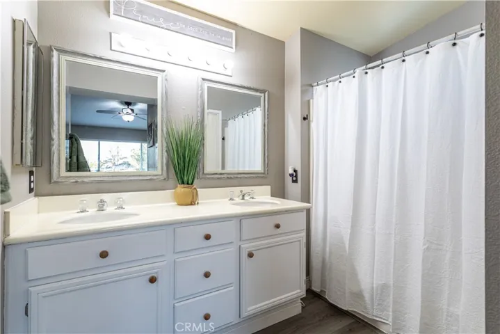 Primary bathroom is conveniently equipped with a double vanity, white cabinets, and private toilet room.