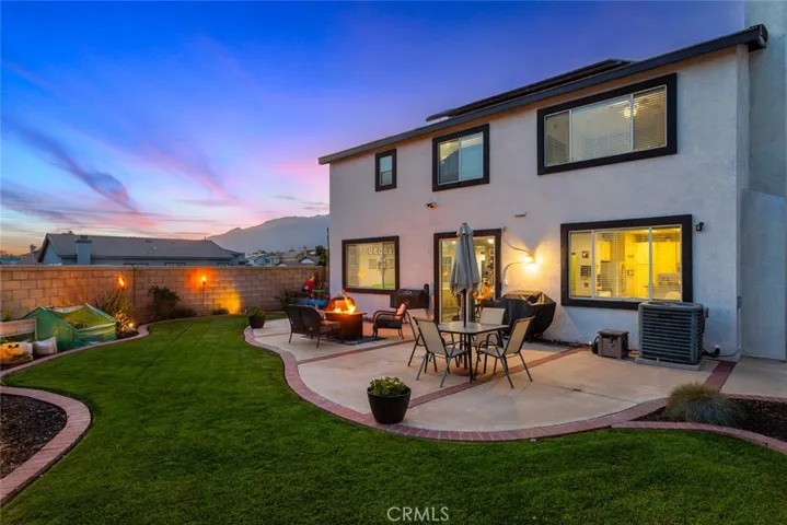 Twilight shot of the backyard with professional landscaping, brick pavers and room for entertaining.