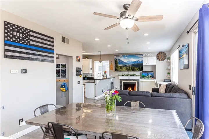 Dining area with ceiling fan and adjoining family room.