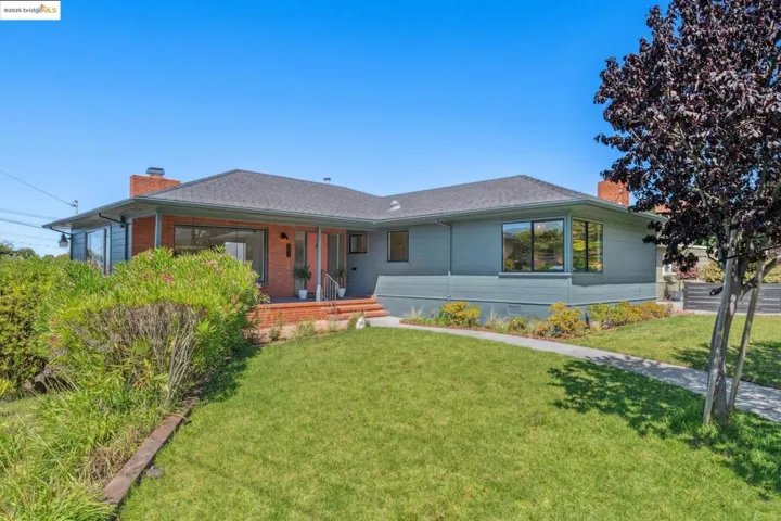 Single story home featuring a chimney, a porch, a front yard, and a shingled roof