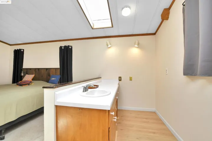 Bedroom featuring ornamental molding, light wood-style floors, and a skylight