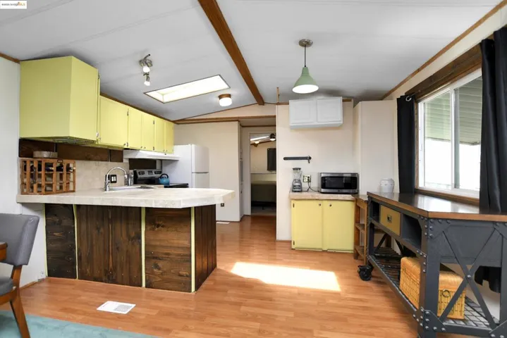 Kitchen with a peninsula, light countertops, light wood-style floors, vaulted ceiling, and pendant lighting