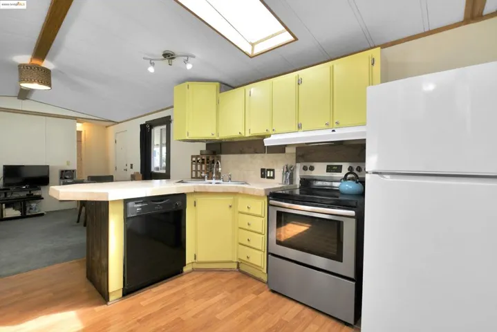 Kitchen featuring freestanding refrigerator, electric range, light countertops, a peninsula, and black dishwasher