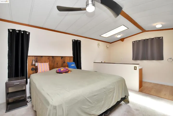 Bedroom featuring vaulted ceiling, light carpet, ornamental molding, and a ceiling fan