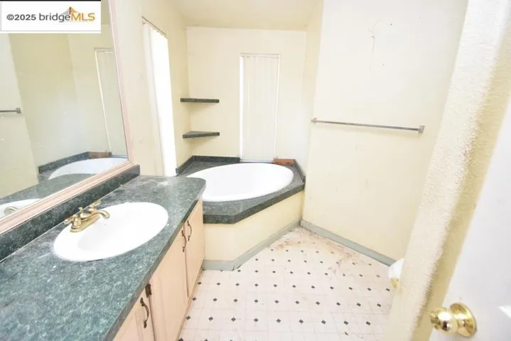 Bathroom featuring a bath, vanity, and light floors