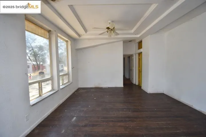 Empty room featuring dark wood finished floors, a tray ceiling, and ceiling fan