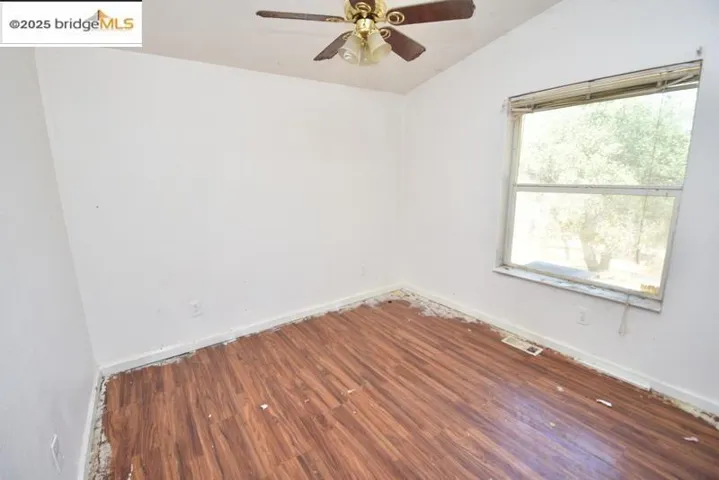 Unfurnished room featuring dark wood-style flooring, ceiling fan, and vaulted ceiling