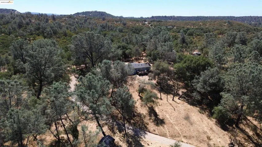 Aerial view of property and surrounding area with a heavily wooded area