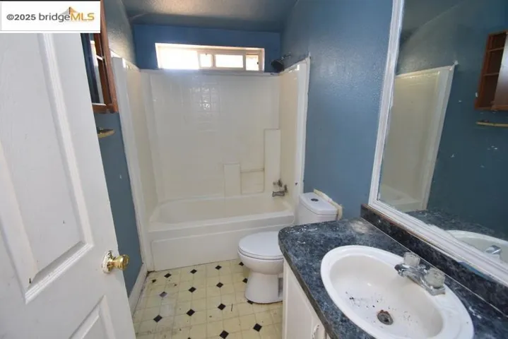 Full bathroom with bathtub / shower combination, vanity, and a textured wall