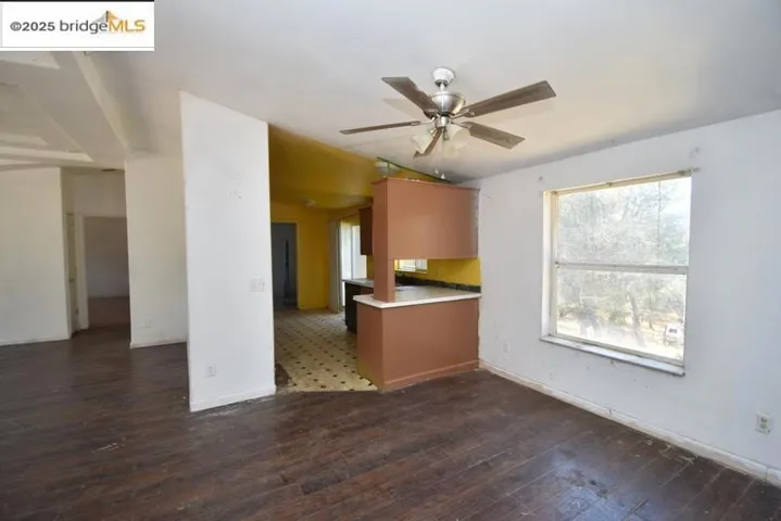 Kitchen with dark wood finished floors, ceiling fan, light countertops, a peninsula, and brown cabinetry