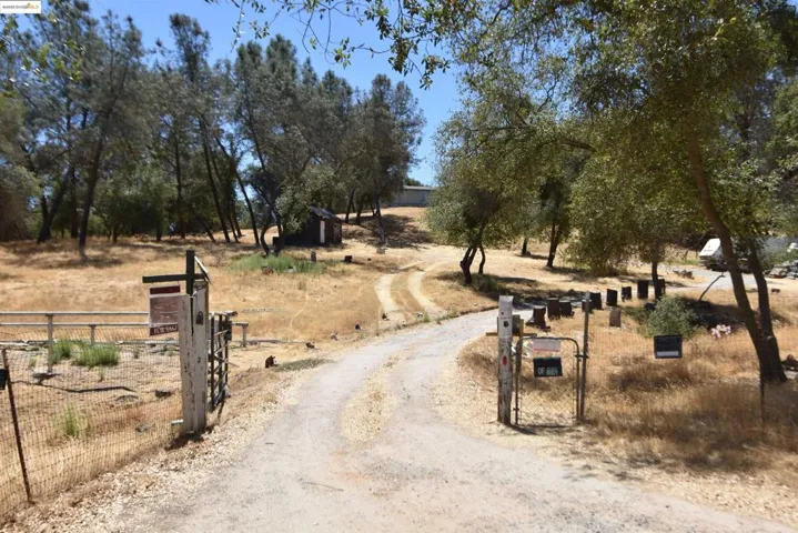 View of dirt / gravel road featuring a gate, a view of countryside, and a gated entry