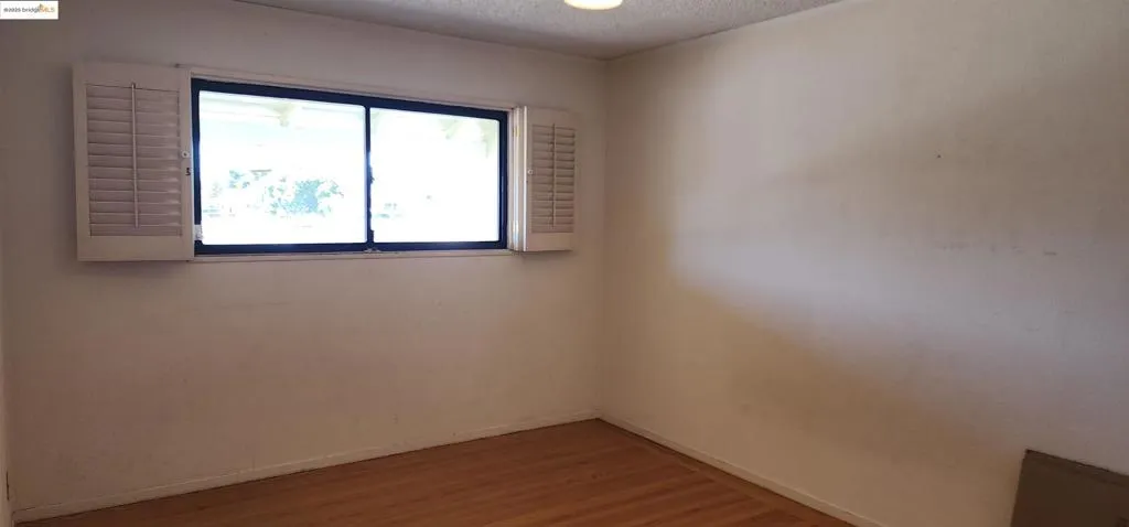 Empty room with a textured ceiling and wood finished floors