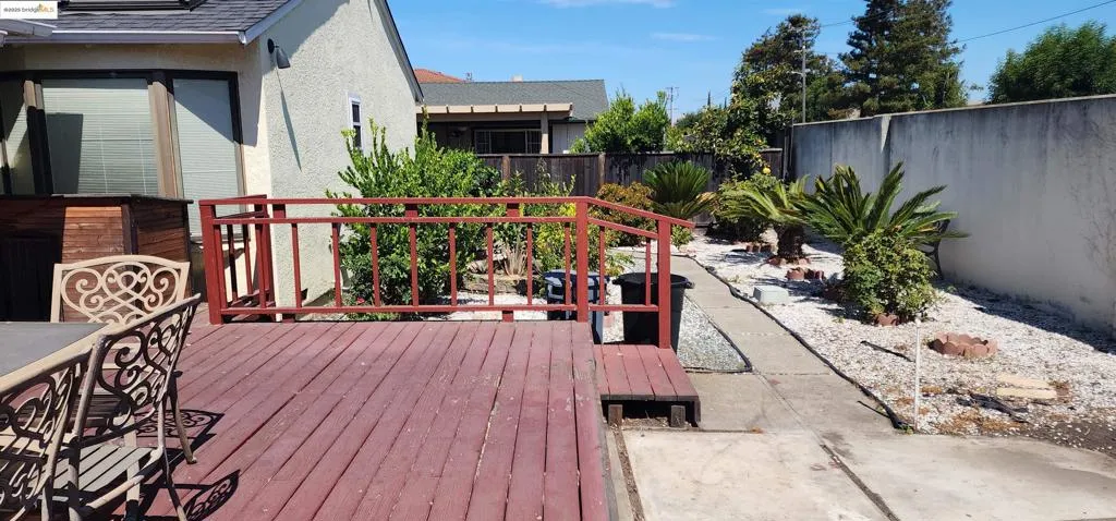 Wooden terrace with a fenced backyard and a patio