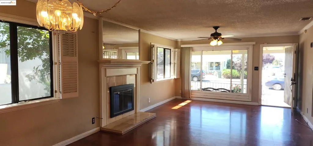Entryway with ornamental molding, a textured ceiling, a fireplace, wood finished floors, and ceiling fan