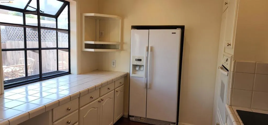 Kitchen featuring tile counters, white appliances, open shelves, and white cabinetry