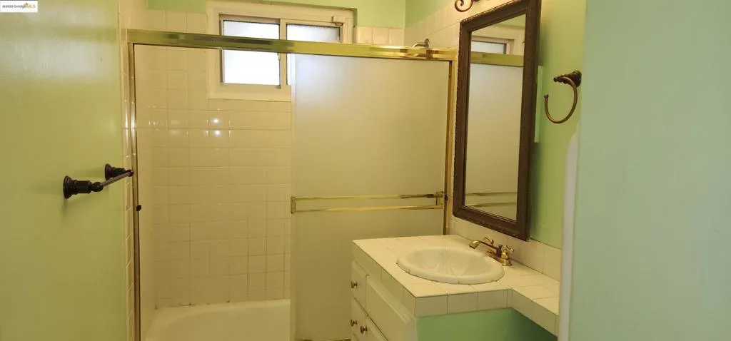 Bathroom with vanity and combined bath / shower with glass door
