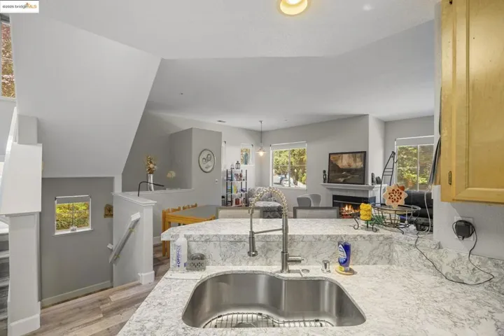 Kitchen with healthy amount of natural light, light wood-style floors, light stone countertops, a fireplace, and lofted ceiling