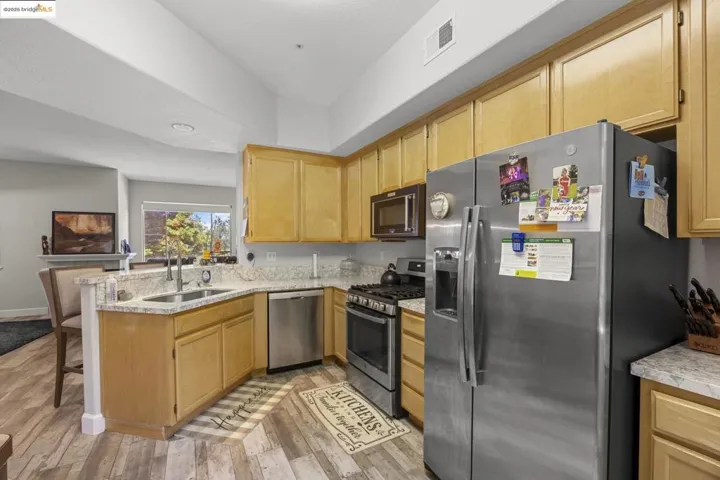 Kitchen with appliances with stainless steel finishes, a peninsula, light wood-style flooring, and light brown cabinets