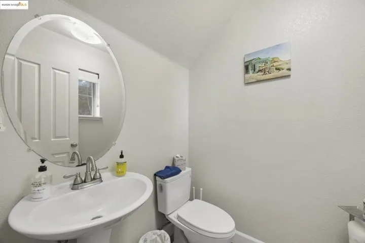 Bathroom with a textured wall, lofted ceiling, and a textured ceiling