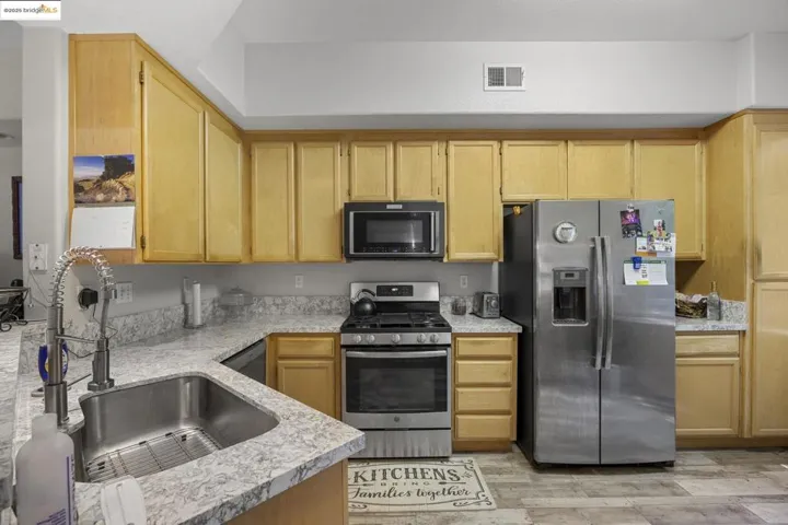 Kitchen with black appliances, light wood-type flooring, and light brown cabinets