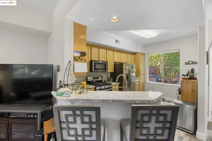 Kitchen featuring light countertops, a peninsula, stainless steel appliances, a kitchen breakfast bar, and light wood-type flooring