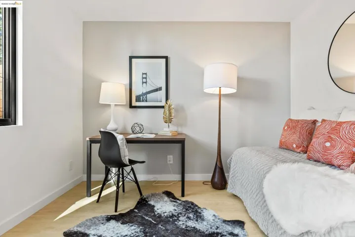 Bedroom with wood finished floors and an office area
