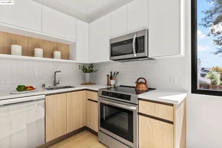 Kitchen featuring appliances with stainless steel finishes, modern cabinets, open shelves, light brown cabinets, and tasteful backsplash
