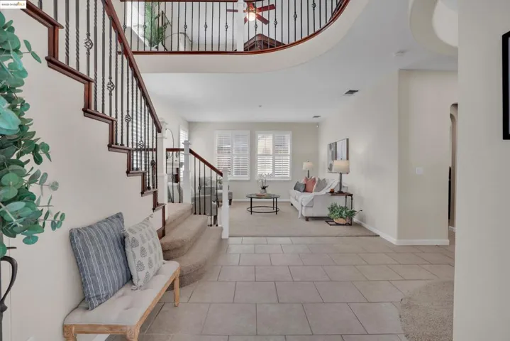 Entryway featuring a ceiling fan, a towering ceiling, light colored carpet, light tile patterned floors, and stairs
