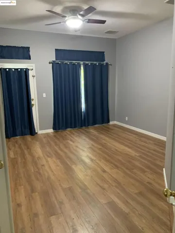 Empty room with wood-type flooring and a ceiling fan