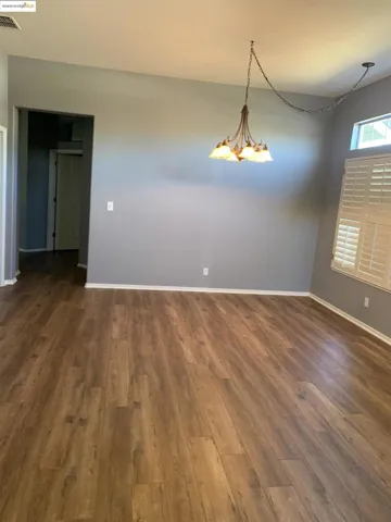 Unfurnished room featuring dark wood-style floors and a chandelier