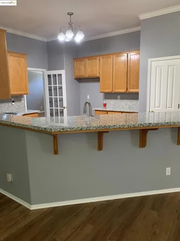 Kitchen featuring light stone countertops, a breakfast bar, ornamental molding, a peninsula, and backsplash