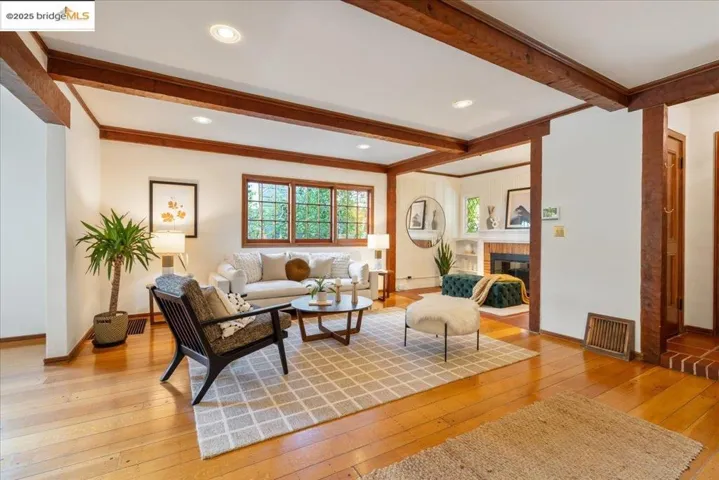 Living area featuring beamed ceiling, light wood-style floors, a brick fireplace, and recessed lighting