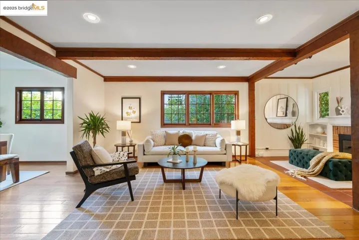 Living area featuring beam ceiling, hardwood / wood-style flooring, crown molding, and a fireplace
